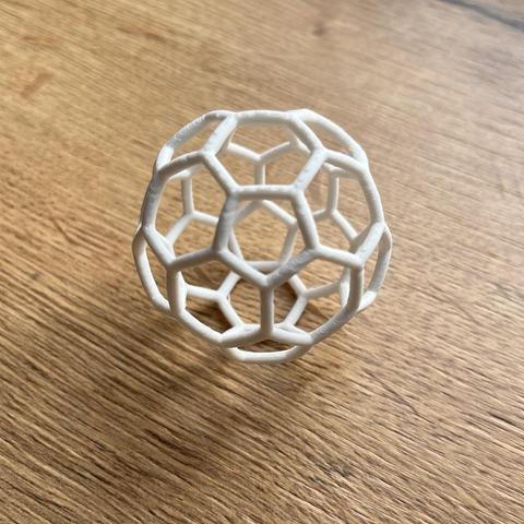 3d printed soccer ball out of white PLA without support at a wooden desk