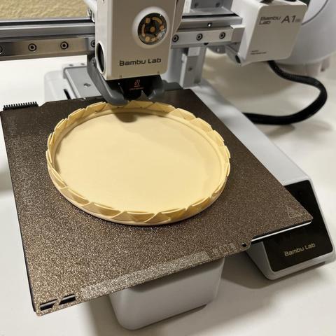 Picture of a Bambulab A1 mini 3d printer, printing a basket with beige brown PLA, only 20% of the model printed, yet, but result looks good so far.