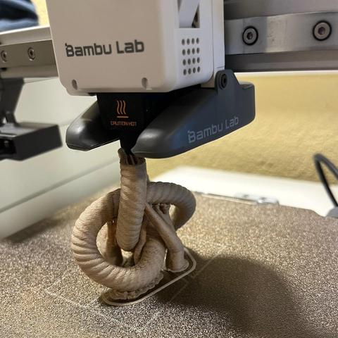 in print picture of a bambulab a1 mini printers build plate with 60% of a trefoil knot printed with wood pla. 